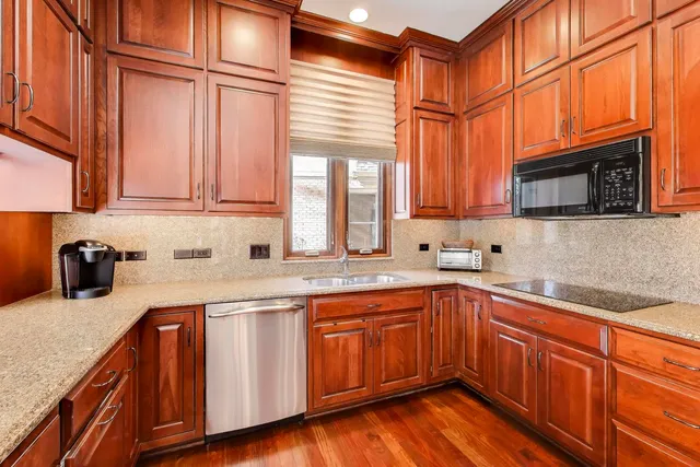 a kitchen with stainless steel appliances granite countertop a sink dishwasher stove and microwave with wooden cabinets