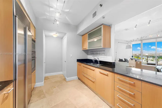 a large kitchen with granite countertop a sink stainless steel appliances and cabinets