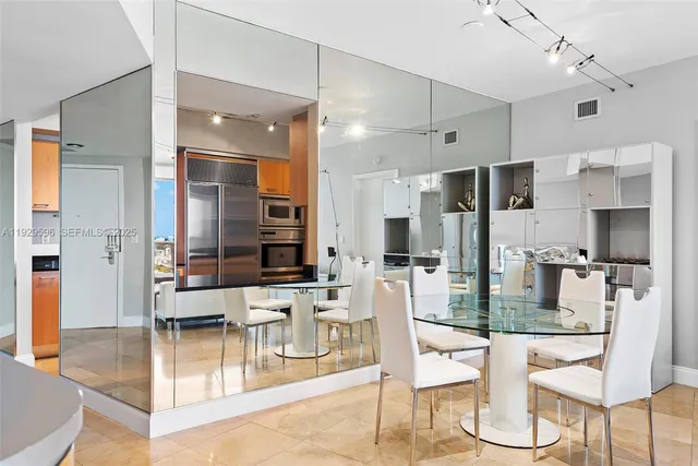 a kitchen with stainless steel appliances kitchen island granite countertop a refrigerator and chairs