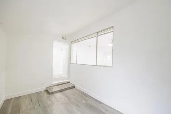 a view of an empty room with wooden floor and a window