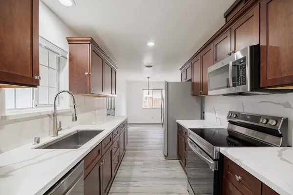 a kitchen with stainless steel appliances a sink a stove and cabinets