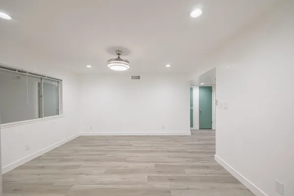a view of an empty room with wooden floor and a window
