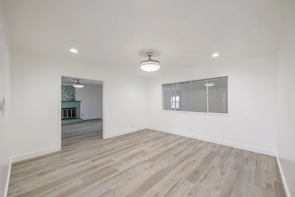 a view of an empty room with wooden floor and a window