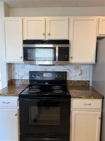 a kitchen with stainless steel appliances granite countertop white cabinets and black stove top oven