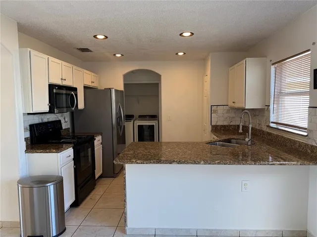 a kitchen with kitchen island granite countertop a stove and a sink