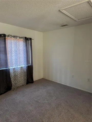 an empty room with windows and chandelier fan