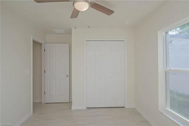 an empty room with a ceiling fan and a window