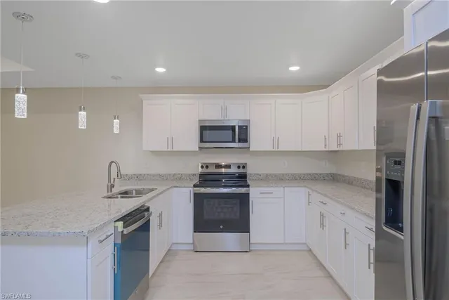 a kitchen with stainless steel appliances granite countertop a refrigerator a sink a stove a microwave and island