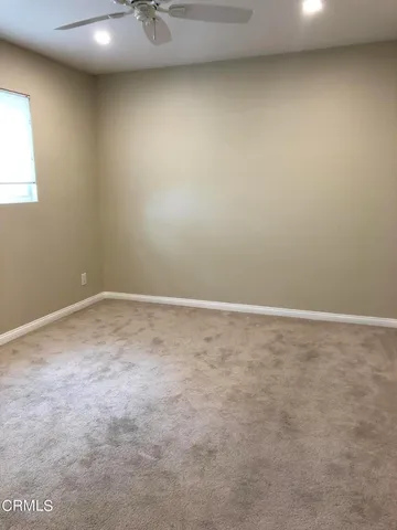 an empty room with a window and a ceiling fan