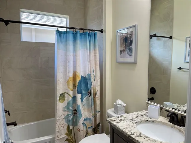 a bathroom with a granite countertop sink a toilet and shower