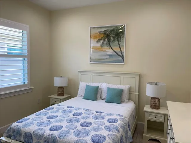 a bedroom with a bed and a lamp on dresser
