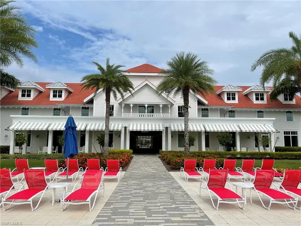 a view of swimming pool with red chairs in front of house