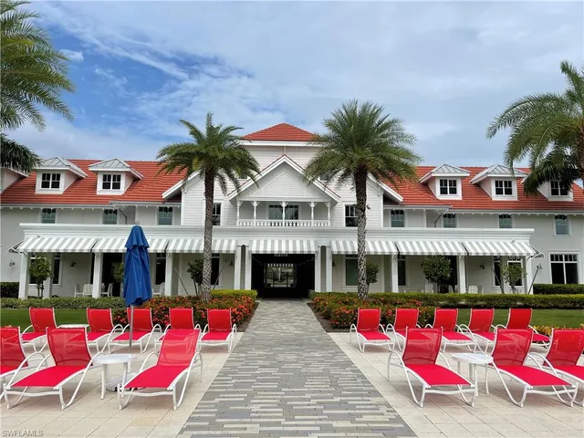 a view of swimming pool with red chairs in front of house