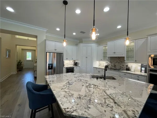 a kitchen with stainless steel appliances kitchen island granite countertop a sink and chairs
