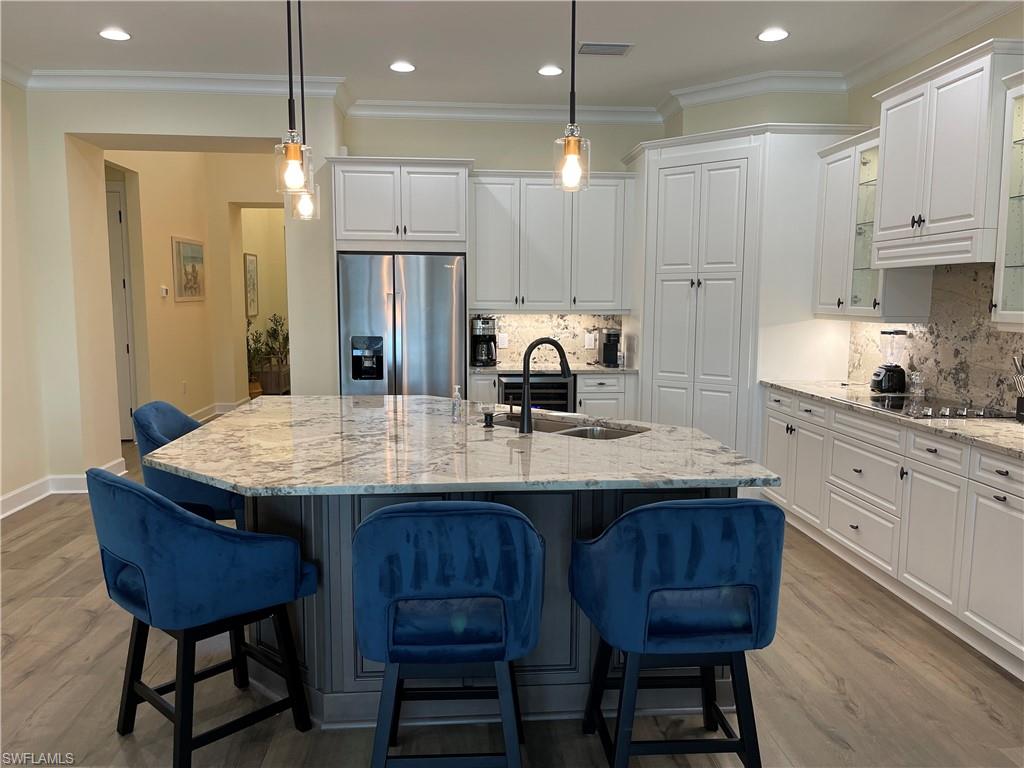 6282 Indies Avenue Naples, FL 34113 - Photo 5 of 33 a kitchen with kitchen island granite countertop a table chairs sink and cabinets