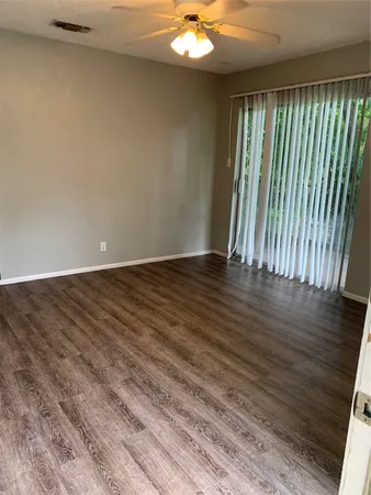 a view of an empty room with wooden floor and a window