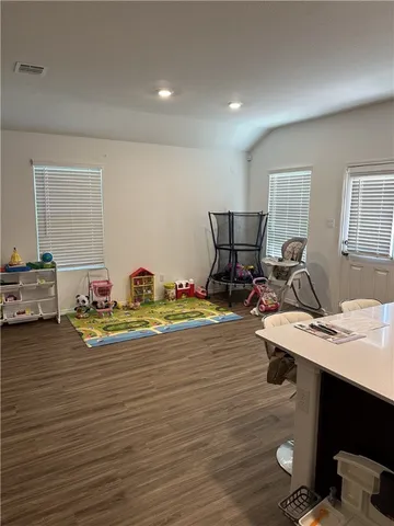 a living room with stainless steel appliances furniture a rug and a view of kitchen