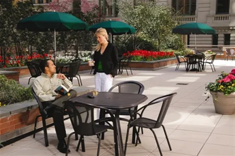 a view of a patio with chairs and table under an umbrella with a garden