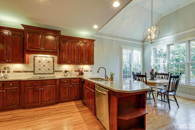 a kitchen with kitchen island wooden floors appliances and cabinets
