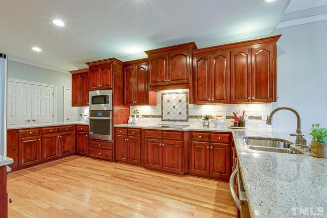 a kitchen with granite countertop wood cabinets stainless steel appliances and a sink