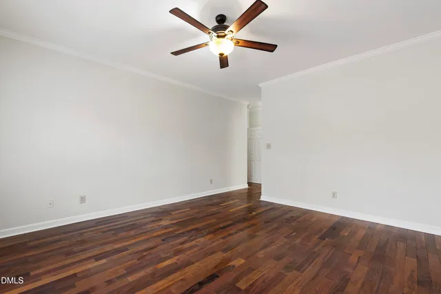an empty room with wooden floor and a ceiling fan