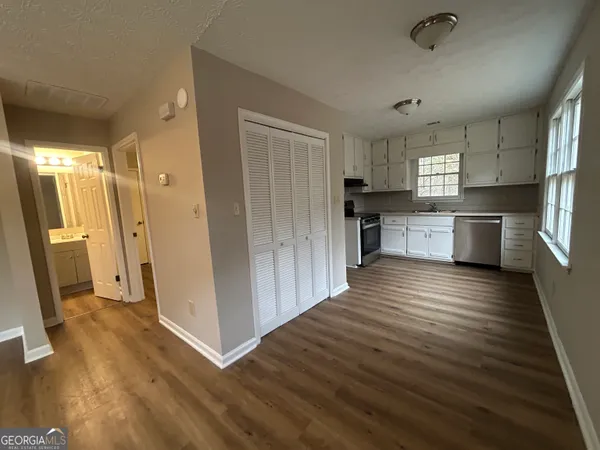 a kitchen with stainless steel appliances granite countertop a refrigerator a sink dishwasher a stove and white countertops with wooden floor