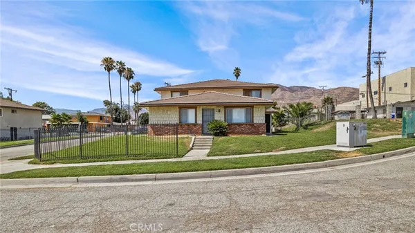 a view of a white house next to a yard with big trees