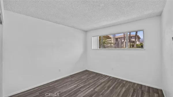a view of an empty room with wooden floor and window