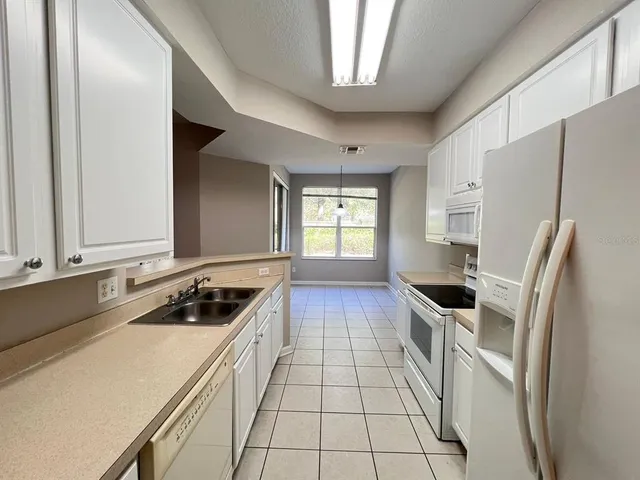 a kitchen with stainless steel appliances a refrigerator a stove and white cabinets