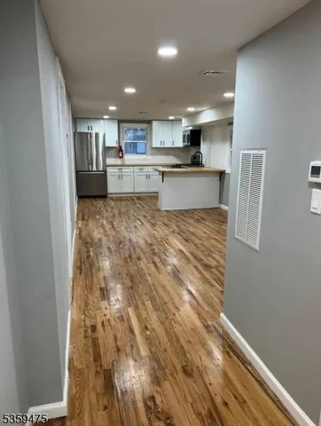 a view of kitchen and empty room with wooden floor