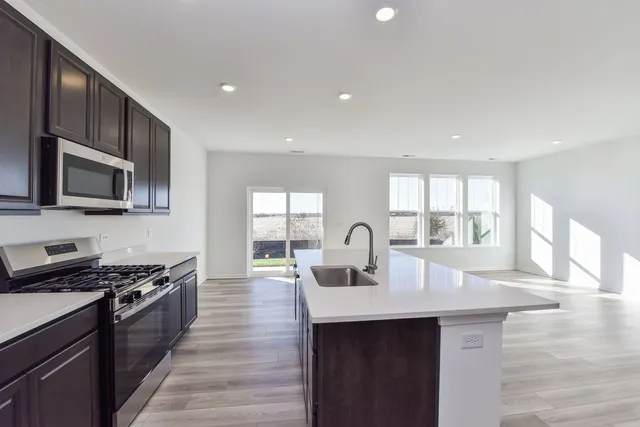 a kitchen with stainless steel appliances a sink dishwasher stove microwave and cabinets with wooden floor