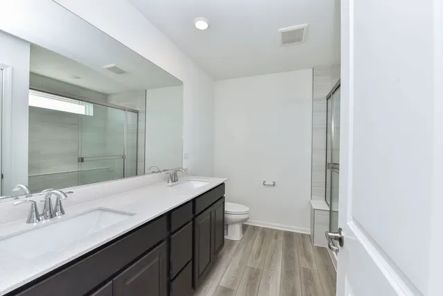 a bathroom with a double vanity sink toilet and shower
