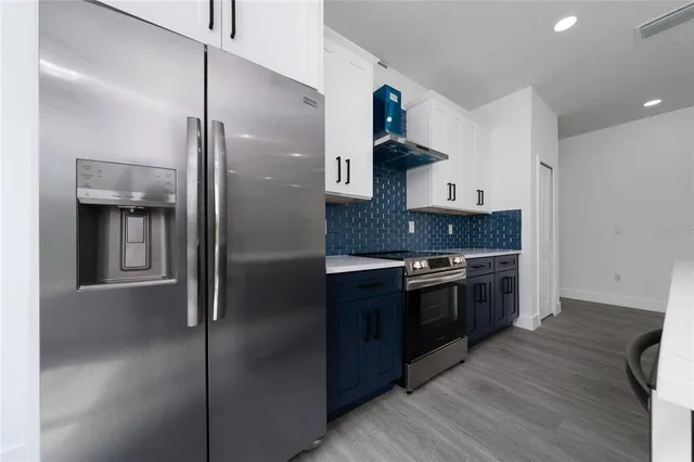 a large kitchen with stainless steel appliances granite countertop a refrigerator and a stove