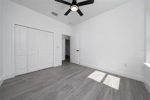 a view of empty room with wooden floor and fan