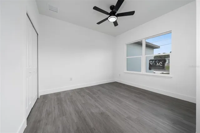 an empty room with wooden floor ceiling fan and windows