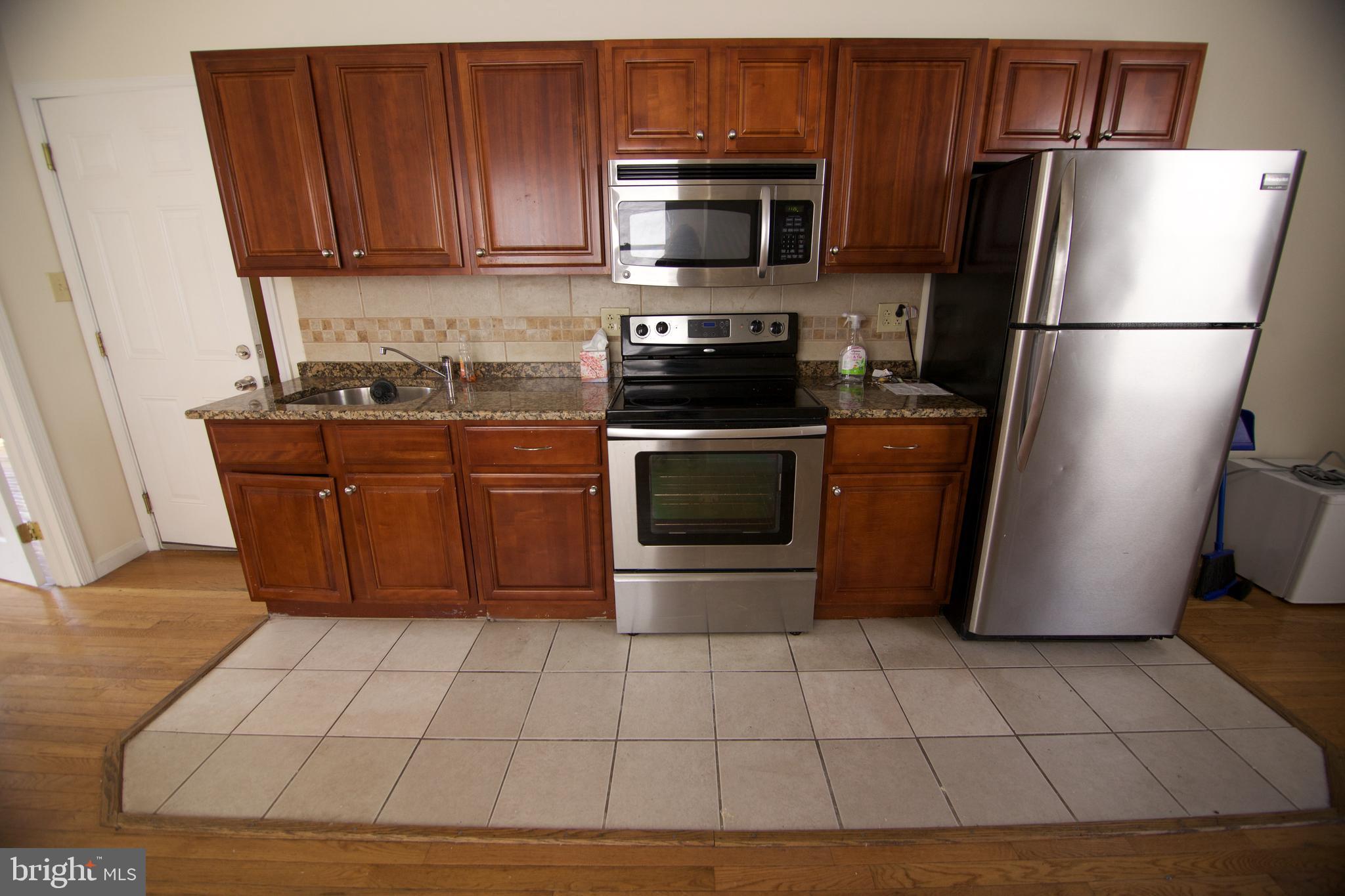 1522 North 17th Street, Unit 2 Philadelphia, PA 19121 - Photo 2 of 10 a kitchen with stainless steel appliances granite countertop a refrigerator stove and microwave