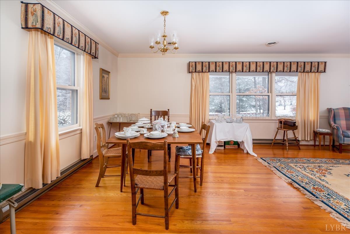 1086 Redfields Road Appomattox, VA 24522 - Photo 7 of 33 a dining room with wooden floor a chandelier a wooden table and chairs