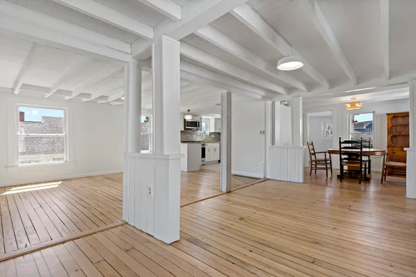 a view of empty room with wooden floor and kitchen view