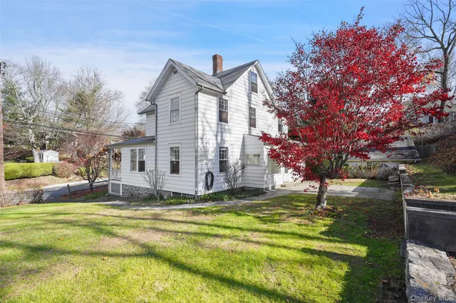 a view of a house with a big yard and large tree