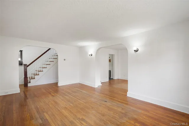 a view of an empty room with wooden floor and stairs