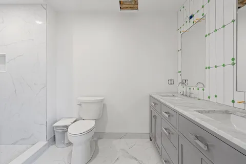 a bathroom with a granite countertop sink a toilet and a shower