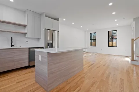 a kitchen with stainless steel appliances kitchen island wooden floors wooden cabinets and entryway