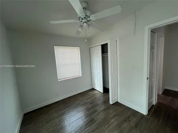 an empty room with wooden floor chandelier fan and windows