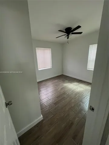 an empty room with wooden floor a ceiling fan and windows