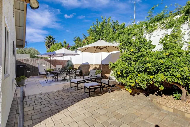 a view of a patio with chairs and table under an umbrella