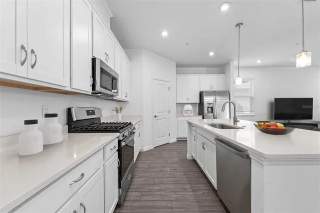 a kitchen with stainless steel appliances a stove a sink a microwave a refrigerator and cabinets