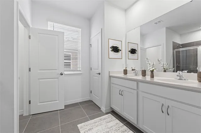 a spacious bathroom with a double vanity sink a mirror and next to a window