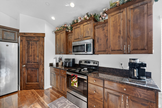 141 Wolverine Creek Elk Ridge, UT 84651 - Photo 11 of 47 Kitchen with stainless steel appliances, light wood-type flooring, dark stone counters, vaulted ceiling, and recessed lighting