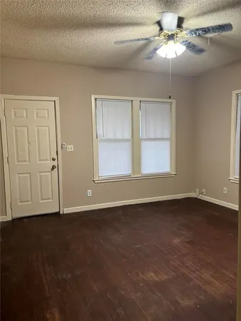 an empty room with wooden floor chandelier fan and windows