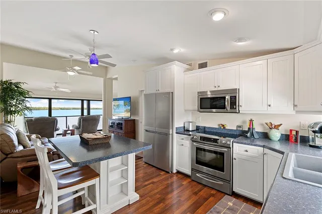 a kitchen that has a lot of white cabinets and stainless steel appliances